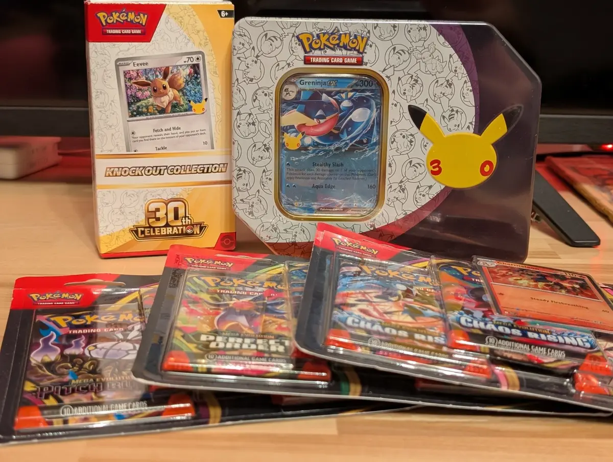 Pokemon TCG blisters, a Greninja tin and an Eevee Knock Out Collection displayed together